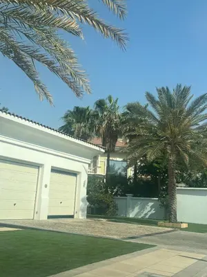 a white house with two garage doors and palm trees at Luxury Palm Villa with direct private beach access in Dubai