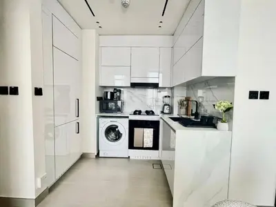 a kitchen with white cabinets and a washer and dryer at Aesthetic 1br In Binghatti House Free Pool Gym in Dubai
