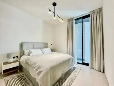 a white bedroom with a bed and a large window at Velvet 1br Serenity Pool View & Free Amenities! in Dubai