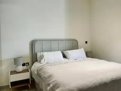 a bedroom with a large bed with white sheets and a lamp at Velvet 1br Serenity Pool View & Free Amenities! in Dubai