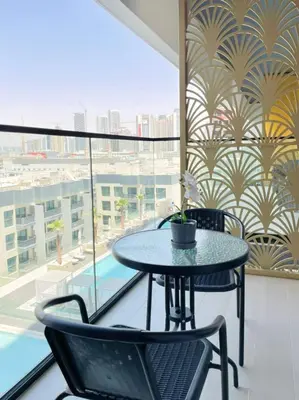 a table and chairs on a balcony with a pool at Velvet 1br Serenity Pool View & Free Amenities! in Dubai