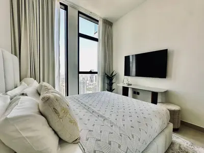 a white bedroom with a bed and a television at Sky 2br Sanctuary With Plunge Pool Gym Parking! in Dubai