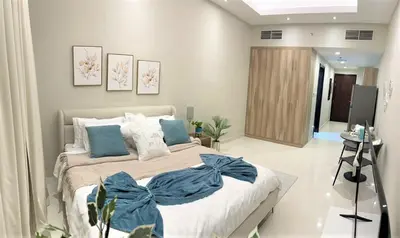 a bedroom with a large bed with blue pillows at Luxury Studio Pool & Gym Access in Dubai Sports City in Dubai