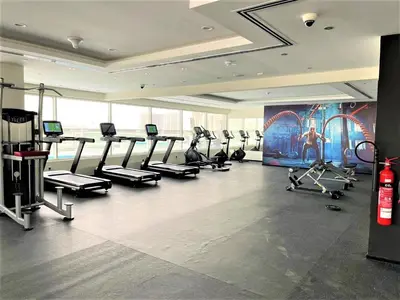 a gym with several tread machines in a room at Luxury Studio Pool & Gym Access in Dubai Sports City in Dubai