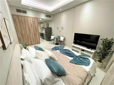 a living room with a large bed and a flat screen tv at Luxury Studio Pool & Gym Access in Dubai Sports City in Dubai