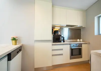 a kitchen with white cabinets and a stove top oven at Fashion Avenue Dubai Mall in Dubai