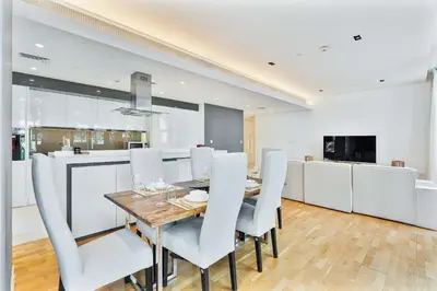 a dining room with a wooden table and white chairs at PVH - Tranquil 2BR - Bluewaters Residences 5 in Dubai