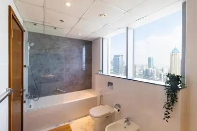 a bathroom with a toilet and a shower and a window at Luxury 4BHK in Business Bay w Burj Khalifa View Noora 4203 in Dubai