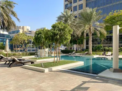 a swimming pool with chairs and palm trees in a city at Silkhaus Luxurious 1BDR in Downtown in Dubai