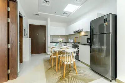 a kitchen with a table and a stainless steel refrigerator at FAM Living 1BR Stay Binghatti Gateway, Al Jaddaf in Dubai