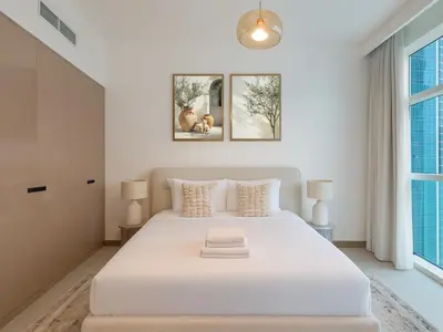a white bedroom with a large white bed and two windows at Luxury Studio in Urban Oasis, Business Bay in Dubai