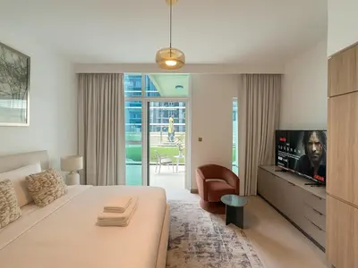 a bedroom with a bed and a tv and a chair at Luxury Studio in Urban Oasis, Business Bay in Dubai