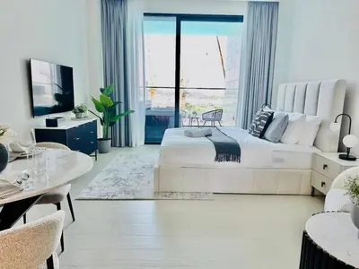a white bedroom with a large bed and a living room at Serene Canalfront Studio Apt With Private Jacuzzi! in Dubai