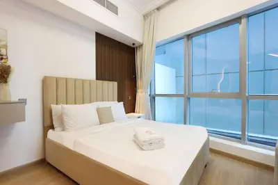 a bedroom with a large bed with a large window at Stylish Studio with Spacious Balcony Walk to JBR Beach in Dubai