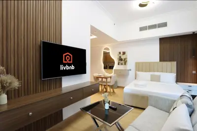 a hotel room with a bed and a tv on a wall at Stylish Studio with Spacious Balcony Walk to JBR Beach in Dubai