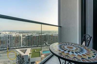 a table on a balcony with a view of a city at Bookable - 2 Bedroom Sobha Waves, Sobha Hartland in Dubai
