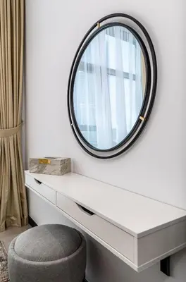 a round mirror on a white wall with a chair at Waves - Impressive 1BR Apartment Close to Burj Khalifa in Dubai