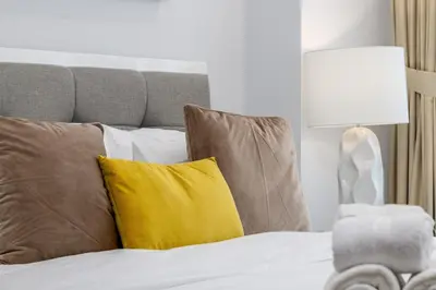 a bed with brown and yellow pillows and a lamp at Waves - Impressive 1BR Apartment Close to Burj Khalifa in Dubai