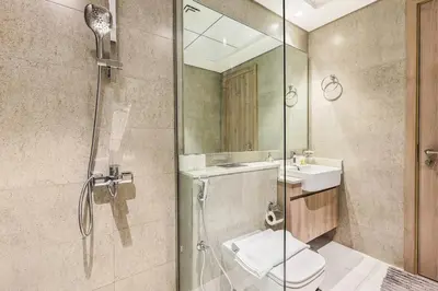 a bathroom with a shower and a toilet and a sink at Luxury 1BR Hills Green View Mall & Downtown Dining Shopping in Dubai
