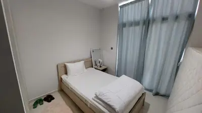 a small white bedroom with a bed and a window at Damac hills 2 vardon cluster in Dubai