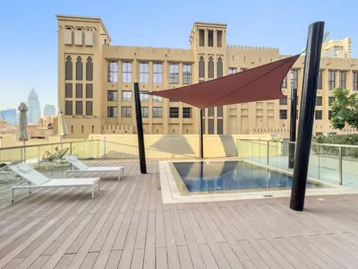 a patio with a umbrella and a pool on a building at FIRST CLASS 1BR Burj Views & Classy Comfort in Dubai