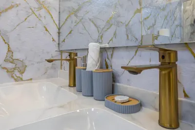 a bathroom with gold faucets and a sink at Modern 1BR with High Floor Near Mall & Tram in Dubai