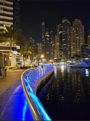 a city at night with blue lights in the water at Modern 1BR with High Floor Near Mall & Tram in Dubai