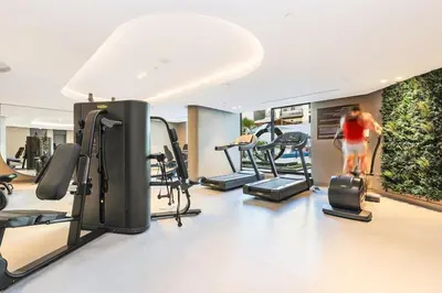 a woman in a gym with several tread machines at Stylish Studio Near Miracle Garden - Luxury Amenities & Style in Dubai