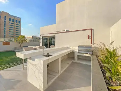 a white kitchen with a sink on a building at Stylish Studio Near Miracle Garden - Luxury Amenities & Style in Dubai
