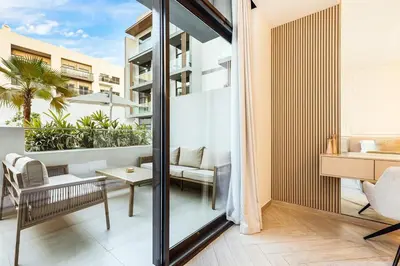 an apartment with a balcony with a desk and a table at Stylish Studio Near Miracle Garden - Luxury Amenities & Style in Dubai