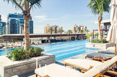 a swimming pool with tables and chairs and palm trees at LUX Iconic Views at The Palm Tower Studio 3 in Dubai