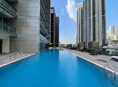a large blue swimming pool in a building with tall buildings at FIRST CLASS Studio Downtown Bliss Urban Gem in Dubai