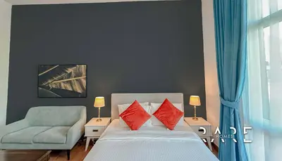a bedroom with a bed with red pillows and a chair at Rare Holiday Homes - Mediterranean Cluster - Near Ibn Battuta Mall - Discovery Garden - Building# Med 65 - RG04 in Dubai