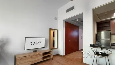 a living room with a tv on a wooden cabinet at Rare Holiday Homes - Mediterranean Cluster - Near Ibn Battuta Mall - Discovery Garden - Building# Med 65 - RG04 in Dubai