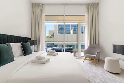 a bedroom with a large white bed and a chair at Silkhaus Lavish 2BDR in Bay Square at Prime location in Dubai
