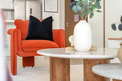 a living room with a orange chair and a white vase on a table at Silkhaus Luxurious 3BR with Maid Room in Dubai Hills in Dubai