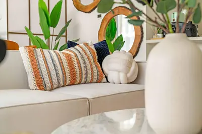 a living room with a couch with pillows and a vase at Silkhaus Luxurious 3BR with Maid Room in Dubai Hills in Dubai