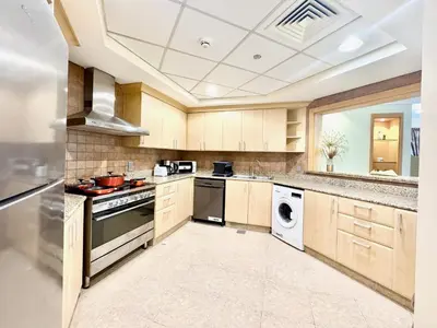 a large kitchen with wooden cabinets and a dishwasher at Palm Paradise Walk to Beach in Dubai