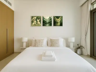 a white bedroom with a large white bed with three pictures at Cozy New Studio Heart of Al Furjan in Dubai