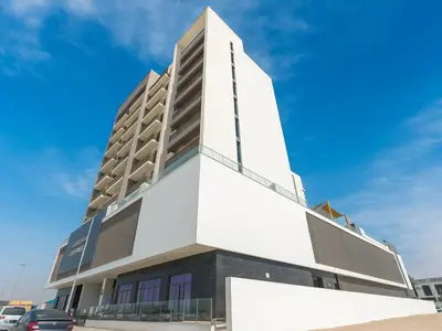 a white building on a street with a blue sky at Cozy New Studio Heart of Al Furjan in Dubai