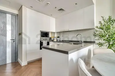 a kitchen with white cabinets and a table at Luxury at Its Finest, 2BR with Private Indoor Pool in Dubai