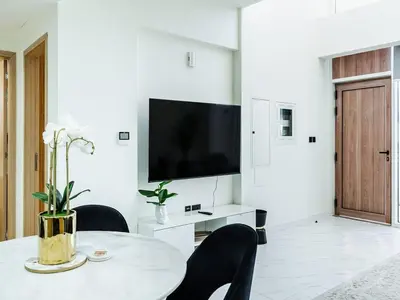 a white living room with a table and a tv at Cozy house suitable for family in Dubai