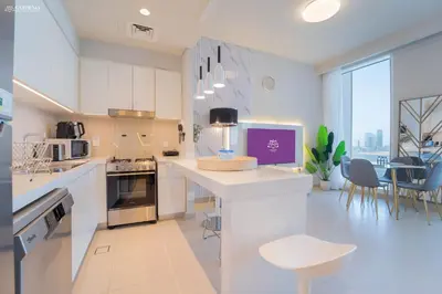 a kitchen with white cabinets and a table and chairs at Gardenia Suites Creek Harbour, 2 Bedroom Stylish Apartment with Creek Views in Dubai