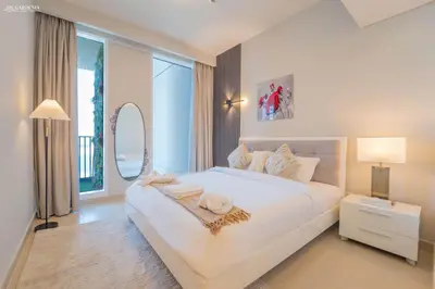 a white bedroom with a large bed and a mirror at Gardenia Suites Creek Harbour, 2 Bedroom Stylish Apartment with Creek Views in Dubai