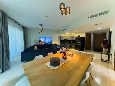 a living room with a wooden table and a blue couch at Spacious 2BR in Lago Vista Tower in Dubai