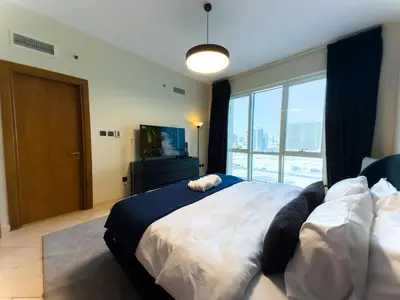 a bedroom with a large bed and a large window at Spacious 2BR in Lago Vista Tower in Dubai
