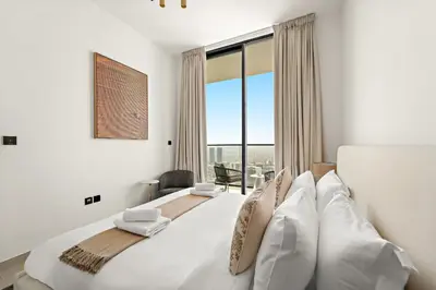 a white bedroom with a large bed and a window at VayK - Stylish Bright 1BR in JVC in Dubai