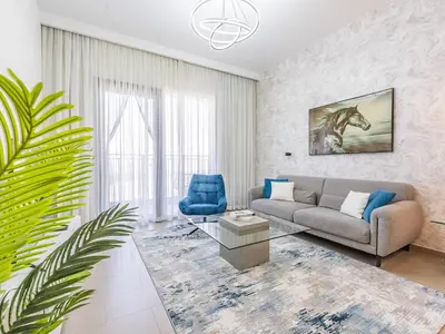 a living room with a couch and a blue chair at Stylish Dubai Hills Retreat 1BR-Park Heights 2 T2 in Dubai