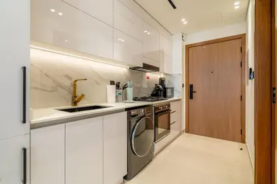 a white kitchen with a sink and a stove at DAYF-LAV Brand New Apartment with Balcony in JVC in Dubai