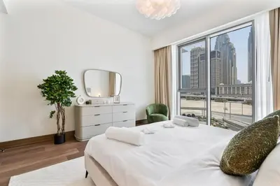 a bedroom with a white bed and a large window at Stylish 1 BR in Canal Front with Pool and Gym Access in Dubai